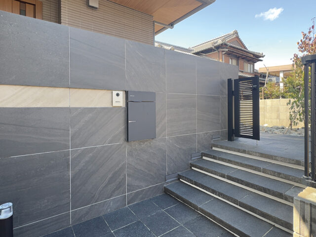 門まわりの壁に、モーディカ  タイル（ダークグレー）を使用。天然石調の深みあるタイルデザインが上質な空間をつくります