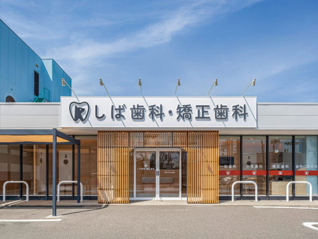 エントランスに木目調の縦格子を設置。夕刻には室内の明かりが外へにじみ、街中での医院の存在感を高めます